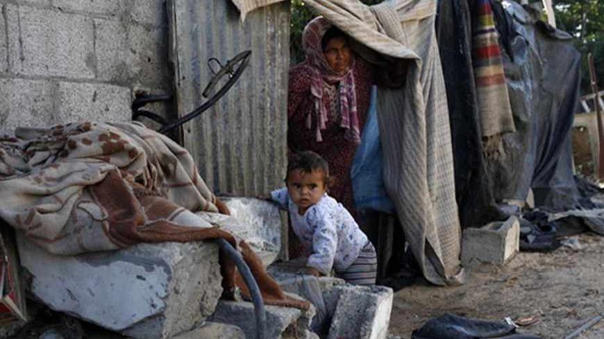 A Palestinian boy plays outside his family's dwelling as his mother looks out in Khan Younis in the southern Gaza Strip June 15, 2013.  REUTERS/Ibraheem Abu Mustafa (GAZA - Tags: SOCIETY) - RTX10OW9