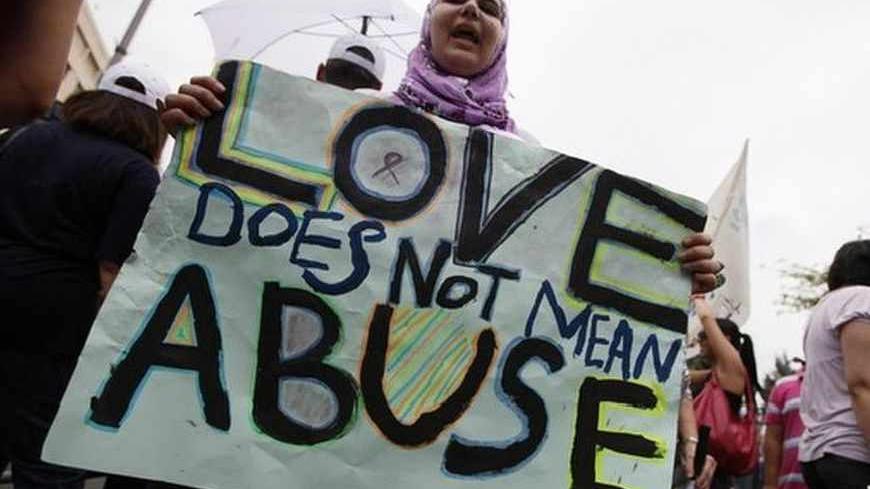 A female activist holding a placard stands amongst men during a protest against family violence near the parliament and government palace in Beirut May 29, 2011. Lebanese women's rights organization, KAFA, held the protest campaign to rally men across the Arab world into the fight to end violence against women.  REUTERS/Jamal Saidi   (LEBANON - Tags: CIVIL UNREST POLITICS) - RTR2N1EY