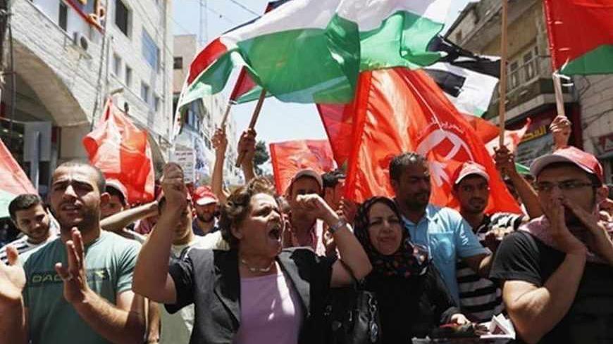 Palestinians wave Palestinian and Popular Front for the Liberation of Palestine (PFLP) flags during a protest against the renewal stalled peace talks with Israel,  in the West Bank city of Ramallah July 28, 2013. Israel was expected on Sunday to approve releasing more than 100 Arab prisoners as a step to renew stalled peace talks with the Palestinians ahead of plans to convene negotiators in Washington later this week. REUTERS/Mohamad Torokman (WEST BANK - Tags: POLITICS CIVIL UNREST) - RTX122EJ