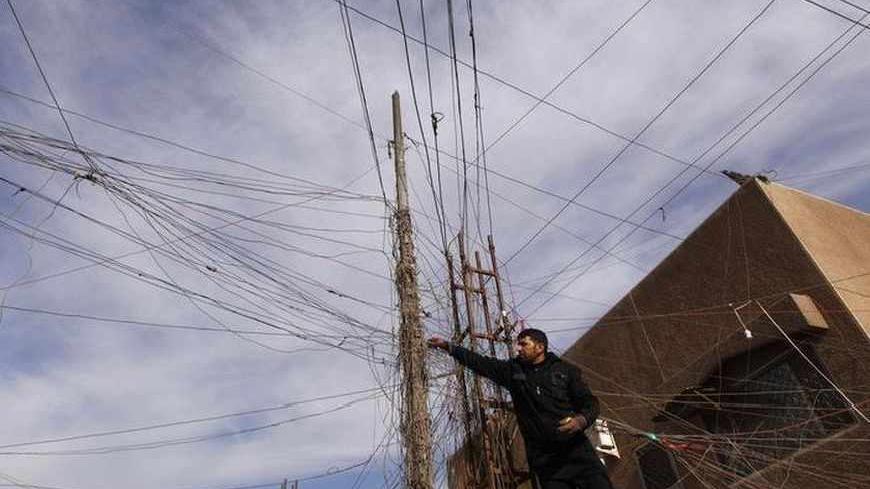 An electrician uses an Avometer to check wires connected to his local generator on a street in Baghdad, December 13, 2011. Iraq's financial system is slowly embracing the free market after years of tight control under Saddam; a fledging stock market is attracting foreign money while the banking and telecommunications industries are growing rapidly. But the national grid provides only a few hours of intermittent power a day, forcing Iraqis to live off noisy diesel-fueled generators. Picture taken December 13