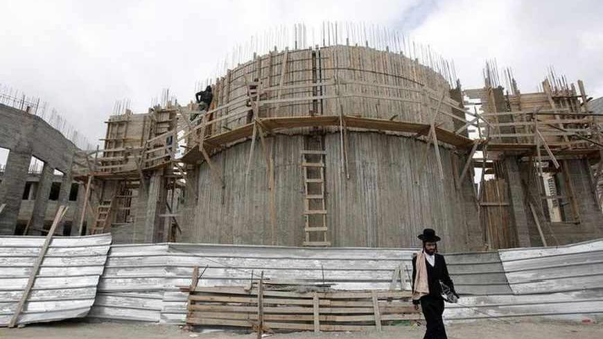 Palestinian labourers work on the construction of a synagogue as an ultra-Orthodox Jewish man walks past in the West Bank Jewish settlement of Beitar Ilit, near Bethlehem March 18, 2013. Israeli Prime Minister Benjamin Netanyahu's new governing coalition prepared to take office after a parliamentary vote on Monday with powerful roles reserved for supporters of settlers in occupied territory. REUTERS/Baz Ratner (WEST BANK - Tags: POLITICS BUSINESS CONSTRUCTION RELIGION) - RTR3F5G0