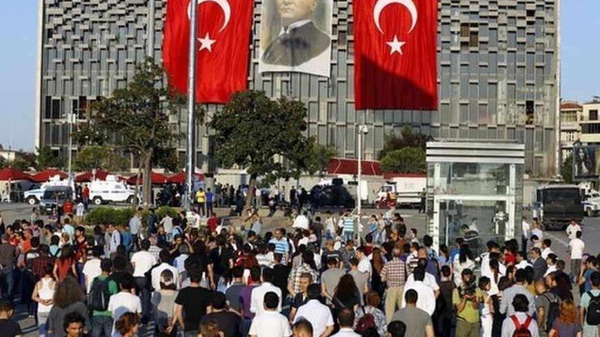 People stand facing Ataturk Cultural Center during a protest at Taksim Square in Istanbul June 18, 2013. Performance artist Erdem Gunduz became the new symbol of anti-government protests in Turkey on Tuesday after his eight-hour vigil in Taksim Square earned him the nickname "the Standing Man". Gunduz said he was protesting in solidarity with demonstrators who were evicted at the weekend from Gezi Park adjoining Taksim, an intervention by police that triggered some of the most violent clashes to date. What
