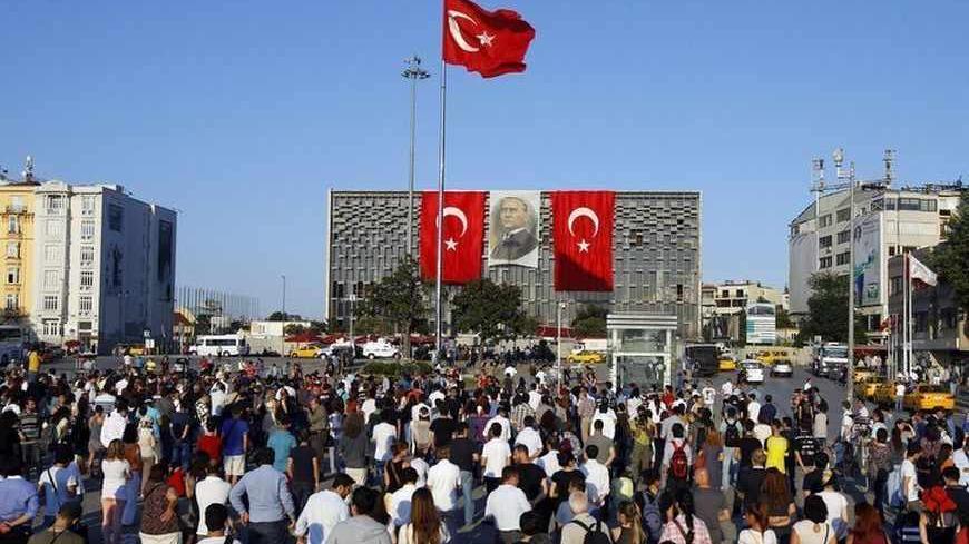 People stand facing Ataturk Cultural Center during a protest at Taksim Square in Istanbul June 18, 2013. Performance artist Erdem Gunduz became the new symbol of anti-government protests in Turkey on Tuesday after his eight-hour vigil in Taksim Square earned him the nickname "the Standing Man". Gunduz said he was protesting in solidarity with demonstrators who were evicted at the weekend from Gezi Park adjoining Taksim, an intervention by police that triggered some of the most violent clashes to date. What 