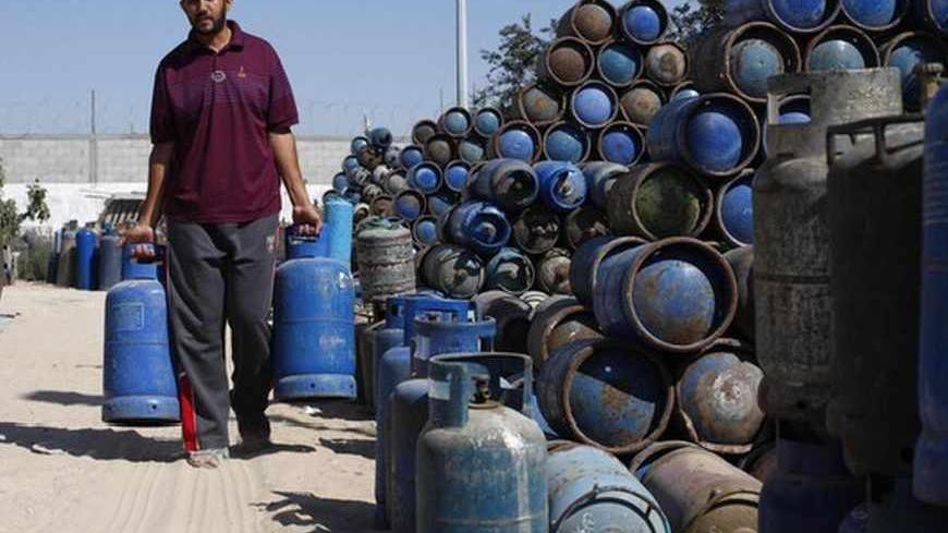 A Palestinian man carries cooking gas canisters at a gas filling station in Khan Younis in the southern Gaza Strip June 24, 2013. Egypt has intensified a crackdown on smuggling tunnels between its volatile Sinai desert and the Gaza Strip, causing a steep hike in petrol and cement prices in the Palestinian territory. Many Gaza residents complain they have been without cooking gas for weeks, with tunnel supplies low and imports from Israel scarce. REUTERS/Ibraheem Abu Mustafa (GAZA - Tags: POLITICS SOCIETY EN