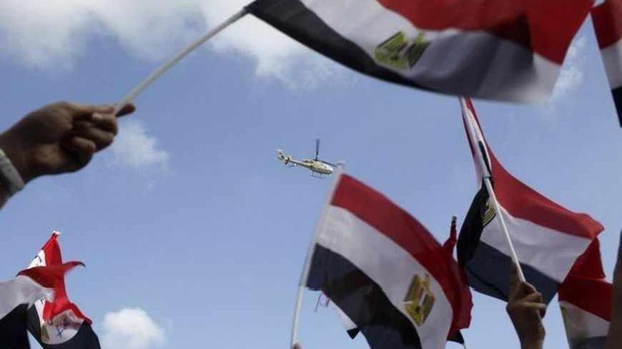 Anti-Mursi protesters wave with their flags happily to a military helicopter passes over where protesters chant slogans in a square where anti-Mursi protesters gather for the third day in Alexandria, July 2, 2013. President Mohamed Mursi clung to office on Tuesday after rebuffing an army ultimatum to force a resolution to Egypt's political crisis, and the ruling Muslim Brotherhood sought to mass its supporters to defend him. REUTERS/Asmaa Waguih (EGYPT - Tags: POLITICS CIVIL UNREST) - RTX11A5Q