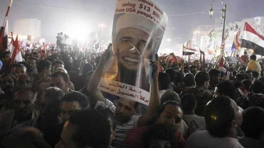 Anti-Mursi protesters cheer and hold up a poster depicting U.S. president Barack Obama with a beard at Tahrir square, where protesters gathered for a mass protest to support the army, in Cairo, July 26, 2013. Egypt's army is recasting the country's political drama, giving popular army chief Abdel Fattah al-Sisi the starring role in a change with echoes of the past that could undermine democracy in the Arab world. Picture taken July 26, 2013. REUTERS/Amr Abdallah Dalsh  (EGYPT - Tags: POLITICS CIVIL UNREST M
