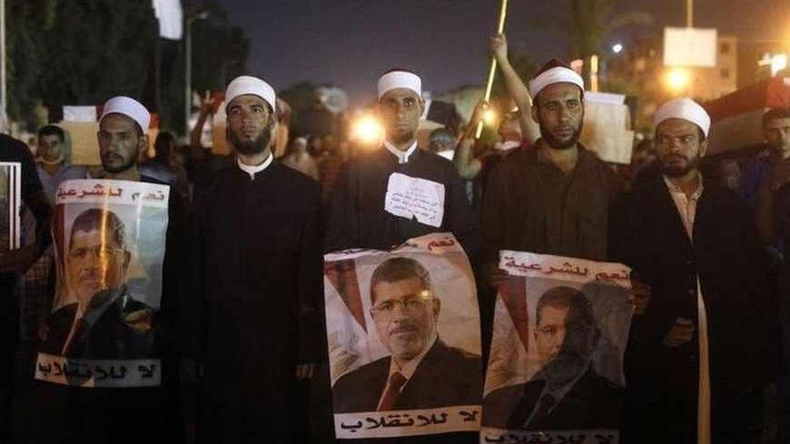 Supporters of deposed Egyptian president Mohamed Mursi walk during an anti-army rally that started from their sit-in area around Raba' al-Adawya mosque, east of Cairo, July 30, 2013. Europe's top diplomat, Catherine Ashton, shuttled between Egypt's rulers and the Muslim Brotherhood on Monday in a mission to pull the country back from more bloodshed, but both sides were unyielding after 80 Islamist supporters were gunned down. The posters read, "Yes to legitimacy , No to coup". REUTERS/Asmaa Waguih (EGYPT - 