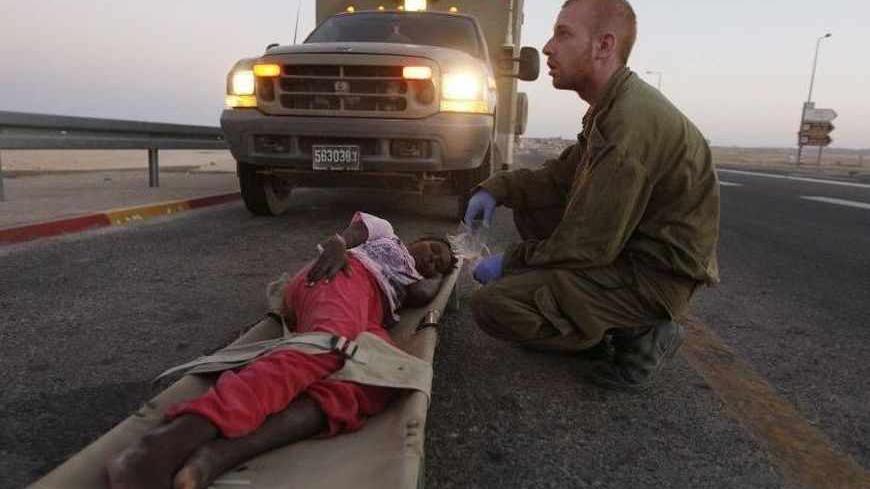 An Israeli soldier gives medical treatment to a young Sudanese migrant suffering from dehydration outside the Sagi Mount military base near the Israeli-Egypt border September 21, 2012. Three armed militants slipped into Israel from Egypt's Sinai peninsula on Friday, killing an Israeli soldier and wounding another before being shot dead, the army said. The commander of Israeli troops in the region said the gunmen ambushed soldiers who had just intercepted some African migrants trying to cross into Israel a