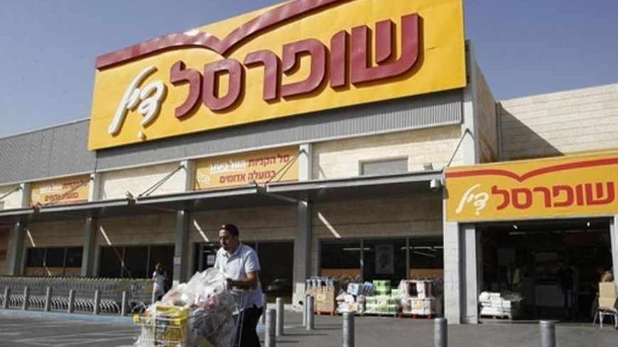 A man pushes a shopping cart outside a Super-Sol supermarket in the West Bank Jewish settlement of Mishor Adumim near Jerusalem May 5, 2013. Ten large business groups, including Israeli tycoon Nochi Dankner's IDB conglomerate, control about 30 percent of the market value of public companies in Israel. Super-Sol, Israel's largest supermarket chain, is part of Dankner's conglomerates' pyramid. Picture taken May 5, 2013. To match ISRAEL-ECONOMY/TYCOONS REUTERS/Ammar Awad (WEST BANK - Tags: BUSINESS POLITICS