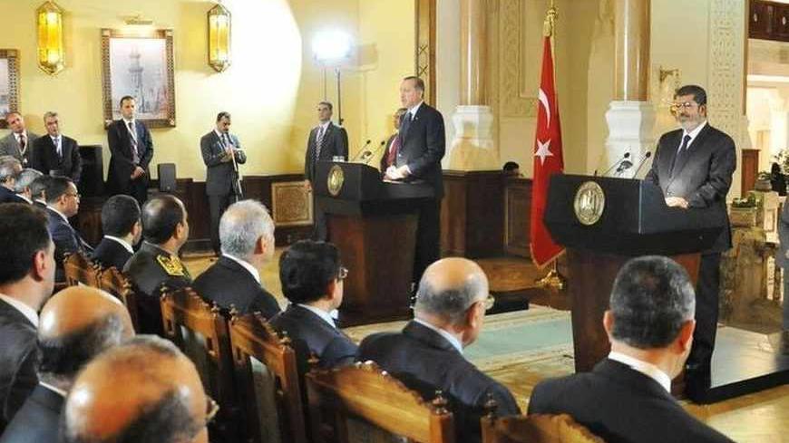 Egyptian President Mohamed Mursi (R) and Turkish Prime Minister Tayyip Erdogan (L) answer questions from journalists during a news conference after their meeting at the Presidential Palace in Cairo November 17, 2012. REUTERS/Egyptian Presidency/Handout (EGYPT - Tags: POLITICS) FOR EDITORIAL USE ONLY. NOT FOR SALE FOR MARKETING OR ADVERTISING CAMPAIGNS. THIS IMAGE HAS BEEN SUPPLIED BY A THIRD PARTY. IT IS DISTRIBUTED, EXACTLY AS RECEIVED BY REUTERS, AS A SERVICE TO CLIENTS - RTR3AJOZ