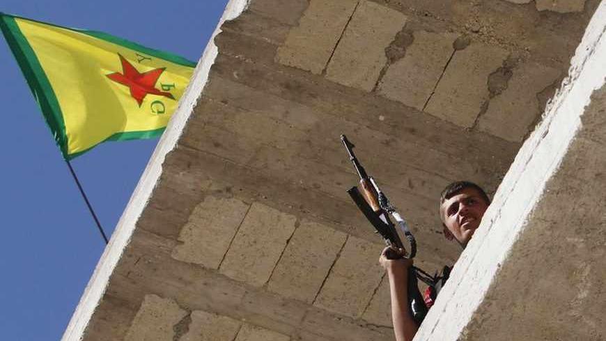 A Kurdish fighter from the Popular Protection Units (YPG) holds his weapon as he takes position atop a building with a YPG flag in Aleppo's Sheikh Maqsoud neighbourhood, June 7, 2013. Kurdish fighters from the YPG joined the Free Syrian Army to fight against forces loyal to Syria's President Bashar al-Assad. Picture taken June 7, 2013. REUTERS/Muzaffar Salman  (SYRIA - Tags: CIVIL UNREST POLITICS CONFLICT) - RTX10USX