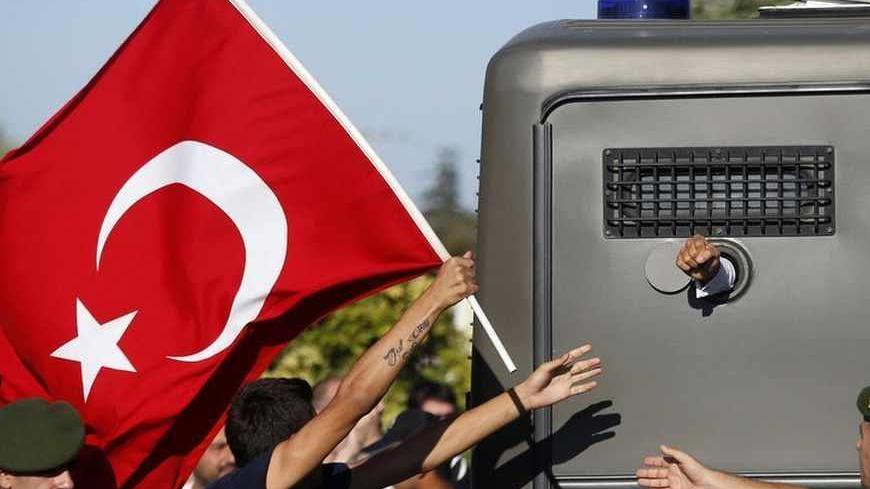 Protesters run after a prison van as an unidentified defendant sticks his fist out as he's driven to a courthouse in Silivri, where a hearing for people charged with attempting to overthrow Prime Minister Tayyip Erdogan's Islamist-rooted government is due to take place, August 5, 2013. A Turkish court on Monday began sentencing nearly 300 defendants accused of plotting to overthrow the government, handing prison sentences of up to 20 years to some and acquitting 21 others. The court was announcing the verdi