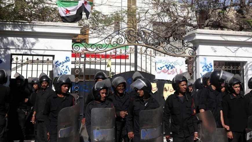 Police stand guard outside the Iranian ambassador's house during a protest against Iran in Cairo April 5, 2013. Ultra-Conservative Islamist Salafists brought down the Iranian flag at the house of the Iranian ambassador in Egypt Mojtaba Amani on Friday, and replaced it with the Syrian revolutionary flag. Seen at the top of the fence is the Syrian revolutionary flag. REUTERS/Mohamed Abd El Ghany (EGYPT - Tags: POLITICS CIVIL UNREST) - RTXY9NK
