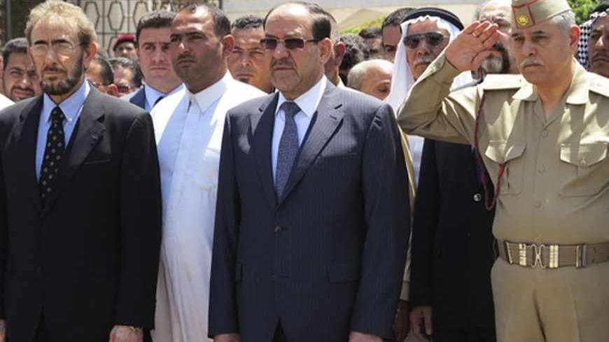 Iraq's Prime Minister Nuri al-Maliki (C) and acting Defence Minister Saadoun al-Dulaimi (L) attend a funeral ceremony for soldiers killed by militants, in Baghdad April 28, 2013. Militants shot dead five Iraqi soldiers in the Sunni Muslim stronghold province of Anbar on Saturday and protesters said they were forming an "army" after four days of unrest that raised fears of a return to widespread sectarian civil conflict. REUTERS/Stringer (IRAQ - Tags: POLITICS MILITARY CIVIL UNREST) - RTXZ2Y6