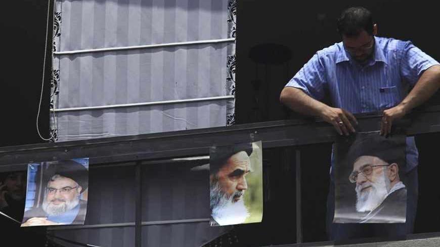 A man hangs pictures of (from R to L) Iran's Supreme Leader Ayatollah Ali Khamenei, founder of the Islamic Republic Ayatollah Ruhollah Khomeini and Lebanon's Hezbollah leader Sayyed Hassan Nasrallah, near 
the site of an explosion in Beirut's southern suburbs, July 9, 2013. A car bomb exploded on Tuesday in a Beirut stronghold district of the Lebanese Hezbollah militant group that has been fighting in Syria's civil war, wounding at least 38 people, a hospital official told Reuters. REUTERS/Khalil Hassan  (L