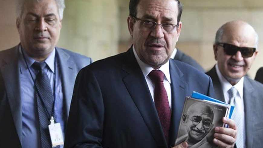 Iraqi Prime Minister Nuri al-Maliki (2nd L) holds a book of Mahatma Gandhi at his memorial at Rajghat in New Delhi August 23, 2013. Maliki expects to finalise a deal to sell India more crude oil during a visit to New Delhi over the next few days, Maliki said on Thursday. REUTERS/Ahmad Masood (INDIA - Tags: POLITICS) - RTX12TXW