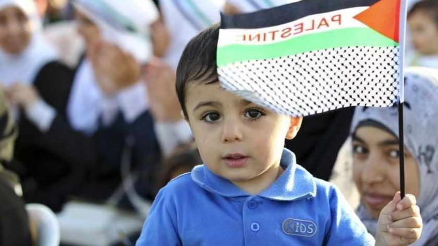 A boy holds a flag, which shows the Palestine flag, as people gather during a rally, organized by the Jordanian Muslim Brotherhood and Islamic Action Front party, to mark the 64th anniversary of Nakba in Amman May 18, 2012. REUTERS/Muhammad Hamed (JORDAN - Tags: POLITICS ANNIVERSARY CIVIL UNREST) - RTR329GM