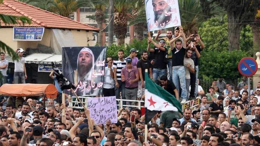 Protesters chant slogans against Syrian President Bashar al-Assad as they hold a poster of deceased al-Qaeda leader Osama bin Laden (top), during a protest in solidarity with Syria's anti-government protesters, in the port-city of Tripoli in north Lebanon October 7, 2011. REUTERS/Omar Ibrahim (LEBANON - Tags: POLITICS CIVIL UNREST) - RTR2SCOJ