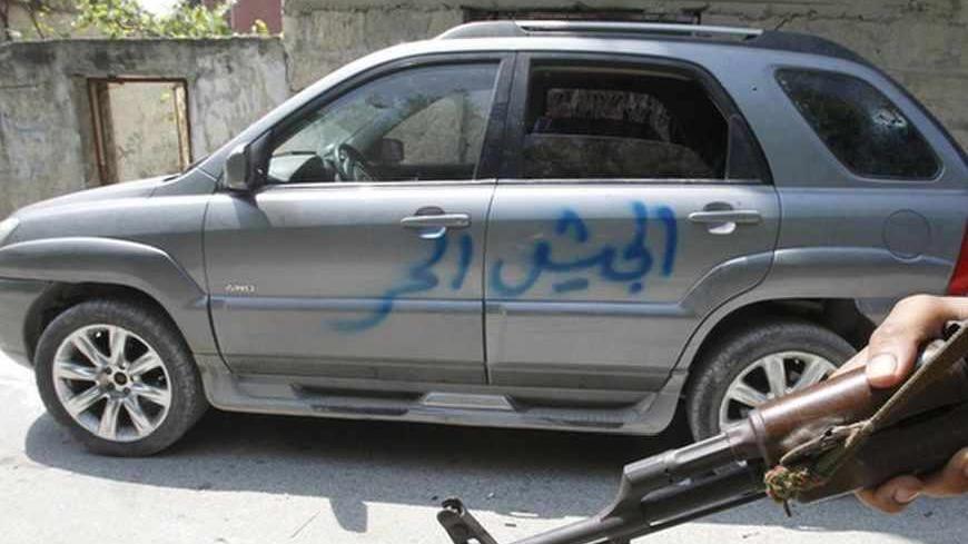 A Syrian soldier stands next to a car with "Free Army" written on it in Haffeh town near Latakia city June 14, 2012. The Syrian town of Haffeh was smouldering and nearly deserted on Thursday after days of clashes between government forces and rebels, while activists reported more army assaults on pro-opposition areas across the country. REUTERS/Khaled al-Hariri (SYRIA - Tags: POLITICS CIVIL UNREST CONFLICT) - RTR33LTX