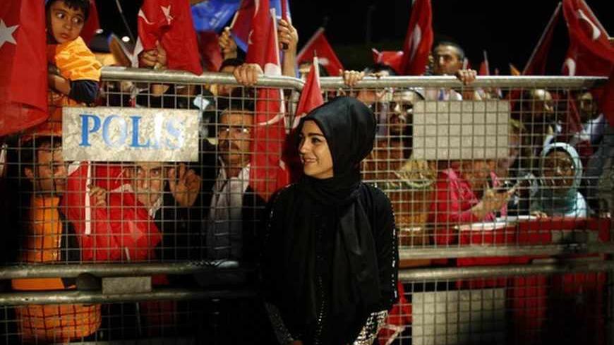 A supporter of Turkish Prime Minister Tayyip Erdogan stands in front of a police fence as she waits for his arrival at Istanbul's Ataturk airport early June 7, 2013. Erdogan told thousands of cheering supporters on Friday his authority came from the ballot box and urged them not to be drawn into violence, in a show of ruling party strength after a week of fierce anti-government protests. Addressing crowds at Istanbul airport from an open-top bus after returning from a trip to North Africa, Erdogan called on