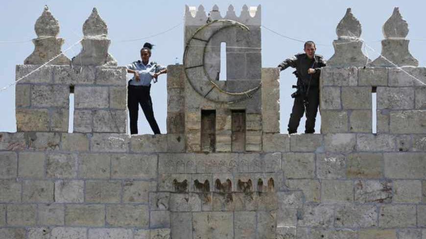 Israeli police officers stand guard atop a wall overlooking Damascus Gate in Jerusalem's Old City, during the holy month of Ramadan July 26, 2013. REUTERS/Baz Ratner (JERUSALEM - Tags: POLITICS RELIGION CRIME LAW) - RTX11ZWT