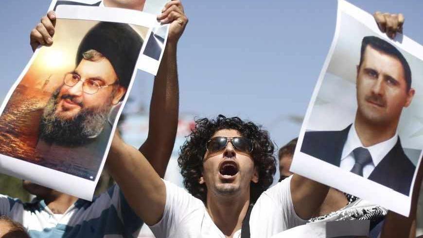 A Palestinian protester holds pictures of Syria's President Bashar al-Assad (R) and Hezbollah leader Sayyed Hassan Nasrallah during a demonstration against potential strikes on the Syrian government, in the West Bank City of Ramallah August 31, 2013.  REUTERS/Mohamad Torokman (WEST BANK - Tags: POLITICS CIVIL UNREST CONFLICT) - RTX132FY
