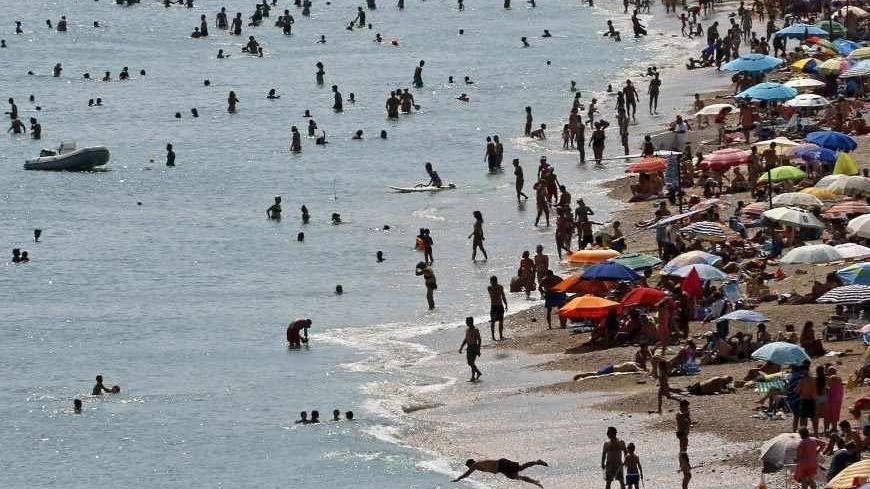 Tourists enjoy the hot weather at Vari beach, some 30 km (19 miles) southeast of Athens July 21, 2013. Foreign tourists are returning to Greece's sun-drenched islands and ancient temples, central bank data showed on Friday, boosting hopes that the key sector may help the crisis-hit country pull itself out of a severe economic recession.    REUTERS/Yannis Behrakis (GREECE - Tags: ENVIRONMENT BUSINESS TRAVEL SOCIETY) - RTX11TYN
