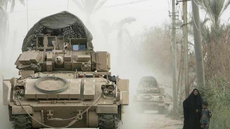 Residents walk beside U.S. army Bradley fighting vehicles on a search mission in the Sunni neighbourhood of Arab Jabour in south Baghdad October 19, 2007.          REUTERS/Fabrizio Bensch (IRAQ) - RTR1V3KU