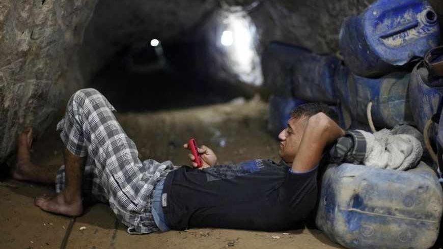 A Palestinian tunnel worker uses his mobile as he rests inside a smuggling tunnel beneath the Gaza-Egypt border in the southern Gaza Strip July 19, 2013. The Islamist group Hamas appealed to Egypt's new rulers on Thursday not to pursue its destruction of smuggling tunnels into the Gaza Strip, warning they risked throttling the small Palestinian territory. REUTERS/Ibraheem Abu Mustafa (GAZA - Tags: POLITICS TPX IMAGES OF THE DAY) - RTX11ROK