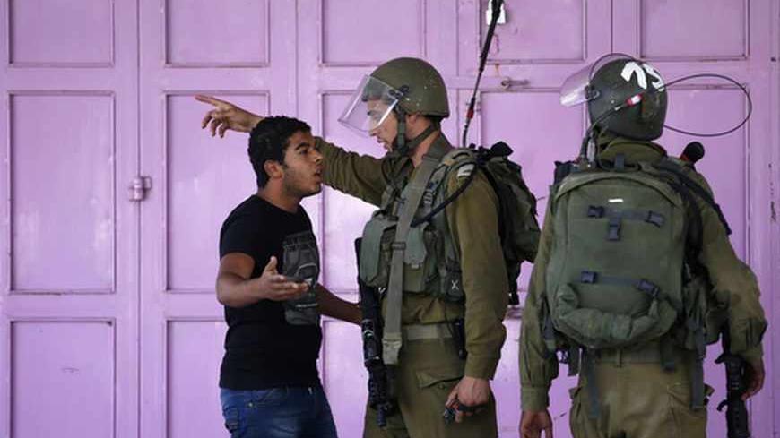 A Palestinian argues with Israeli soldiers as he tries to walk through a closed off area during clashes in the West Bank city of Hebron September 23, 2013. An Israeli soldier was shot dead on Sunday during a Jewish festival in Hebron, a hotbed of tensions where some 500 Israeli settler families live among 100,000 Palestinians. He was the second Israeli serviceman killed since Friday by suspected Palestinian gunmen as tensions rise in the occupied territory despite a resumption of stalled U.S.-brokered peace
