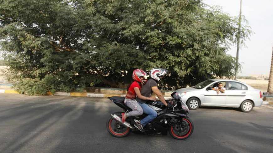 An Iraqi couple ride a motorbike during a biker show on Abu Nawas Street in Baghdad October 19, 2012.  Drag-racing in California, you say? No, this is Baghdad, where youthful rebellion and American biker style clash with  conservative mores in Iraq, a country where just a few years ago militias imposed their own radical Islamic views at gunpoint. Picture taken October 19, 2012. To match Feature IRAQ-CULTURE/BIKERS   REUTERS/Saad Shalash (IRAQ - Tags: SOCIETY SPORT MOTORSPORT) - RTR39IOY
