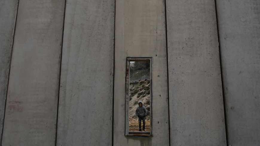 A Palestinian boy is seen through an opening in Israel's controversial barrier in Shuafat in the West Bank near Jerusalem February 17, 2009. REUTERS/Baz Ratner (WEST BANK) - RTXBQ43