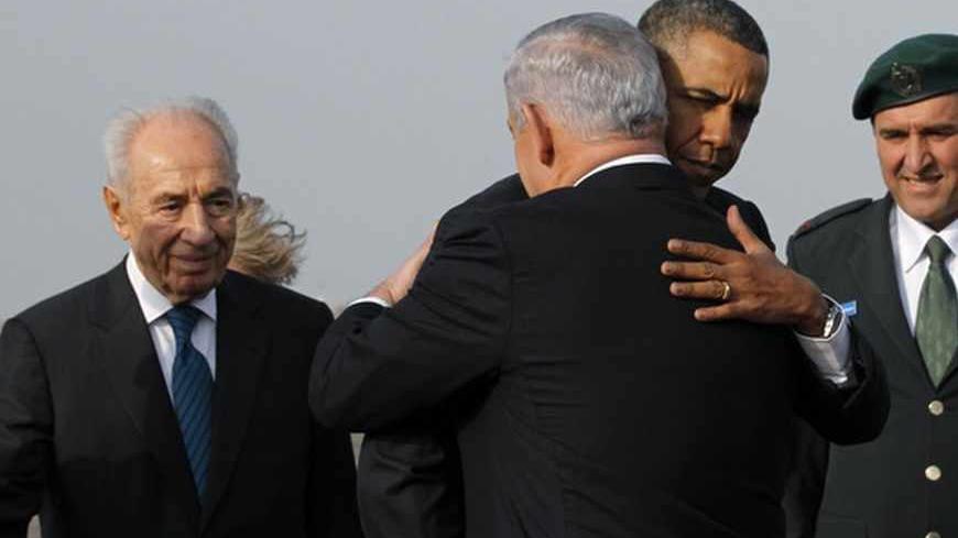 U.S. President Barack Obama hugs Israeli Prime Minister Benjamin Netanyahu as President Shimon Peres (L) watches on, before Obama's departure from Tel Aviv International Airport, March 22, 2013. REUTERS/Jason Reed (ISRAEL - Tags: POLITICS) - RTR3FBUO