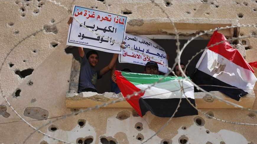 Palestinians wave a national flag and an Egyptian flag (R) as they take part in a rally calling on Egyptian authorities to open the Rafah crossing, outside the crossing in the southern Gaza Strip September 16, 2013. Cairo closed the Rafah crossing, Gaza's main window to the world, completely last week after assailants crashed two explosive-laden cars into a security building adjacent to the border zone, killing six Egyptian soldiers. Ashraf al-Qidra, spokesman for the Hamas-run Gaza Health Ministry, said 1,