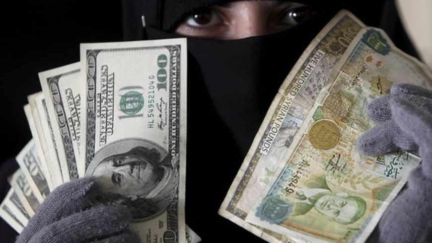 A woman shows U.S. dollars and Syrian pounds in Amman December 12, 2011. The Syrian pound's depreciation has accelerated in the past week as the nine-month-old uprising against President Bashar al-Assad takes its toll on the economy, after months of relative stability when the central bank managed to support the exchange rate by supplying foreign currency. Picture taken December 12, 2011. To match Feature SYRIA-CURRENCY/      REUTERS/Ali Jarekji (JORDAN - Tags: POLITICS BUSINESS) - RTR2V9K6