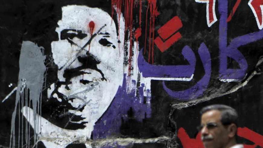 A man walks past graffiti depicting ousted Egyptian President Mohamed Mursi in downtown Cairo September 2, 2013.  Egypt's army-backed authorities referred deposed Mursi to trial on Sunday on charges of inciting murder and violence, in an escalation of the crackdown on his Muslim Brotherhood. The Arabic words read: "Red card, 30 June" REUTERS/Amr Abdallah Dalsh (EGYPT - Tags: POLITICS CIVIL UNREST) - RTX134KT