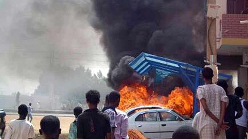People look at burning cars during protests over fuel subsidy cuts in Khartoum September 25, 2013. At least 27 people have been killed in protests in Khartoum over fuel subsidy cuts, a medical source said on Thursday as another bout of the worst unrest seen in Sudan's relatively well-off central regions for years broke out in its biggest port. Thousands had marched in Khartoum on Wednesday, torching cars, buildings and petrol stations. Picture taken September 25, 2013. REUTERS/Stringer (SUDAN - Tags: CIVIL 
