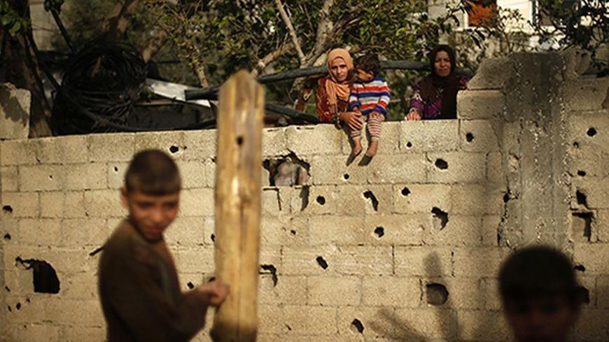 Palestinian women watch their neighbours as they bake bread in a clay oven inside their dwelling in Beit Lahiya, near the border between Israel and northern Gaza Strip April 7, 2013. REUTERS/Mohammed Salem (GAZA - Tags: SOCIETY POVERTY) - RTXYC6N