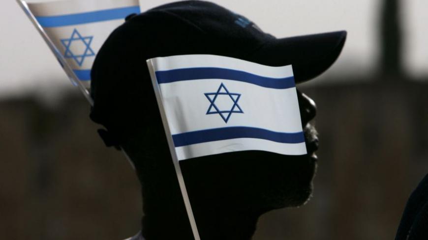 A Nigerian pilgrim holds Israel's national flag during a gathering in the Old City of Jerusalem March 18, 2008. According to Israel's Ministry of Tourism, some 1,000 tourists from Nigeria took part in a gathering to kick off Israel's 60th anniversary celebrations. REUTERS/Ronen Zvulun (JERUSALEM) - RTR1YH1M