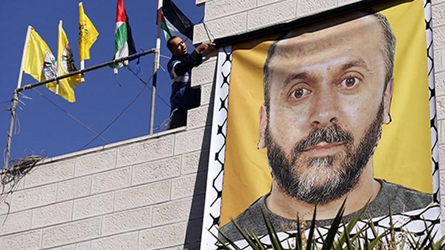 A relative hangs a banner depicting Palestinian prisoner Moses Qar'an outside his house, in the West Bank city of Ramallah October 28, 2013. Israel is to release 26 Palestinian prisoners in the second stage of a deal brokered by the U.S. in July that brought about the resumption of peace talks. REUTERS/Mohamad Torokman (WEST BANK - Tags: CIVIL UNREST POLITICS) - RTX14R4A