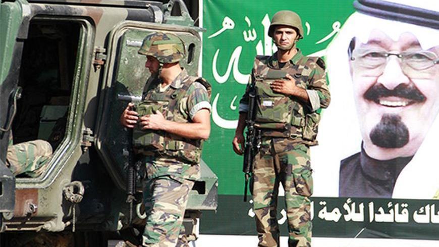 Lebanese Army soldiers patrol in front of a poster depicting Saudi Arabia's King Abdullah in the Sunni Muslim Bab al-Tebbaneh neighbourhood, in Tripoli, northern Lebanon October 23, 2012. Four people were killed and 15 wounded in overnight gun battles in the Lebanese city of Tripoli in a second night of fighting between Sunni and Alawite gunmen loyal to different sides in the war in neighbouring Syria, a military source said on Tuesday. REUTERS/Omar Ibrahim   (LEBANON - Tags: POLITICS CIVIL UNREST MILITARY)