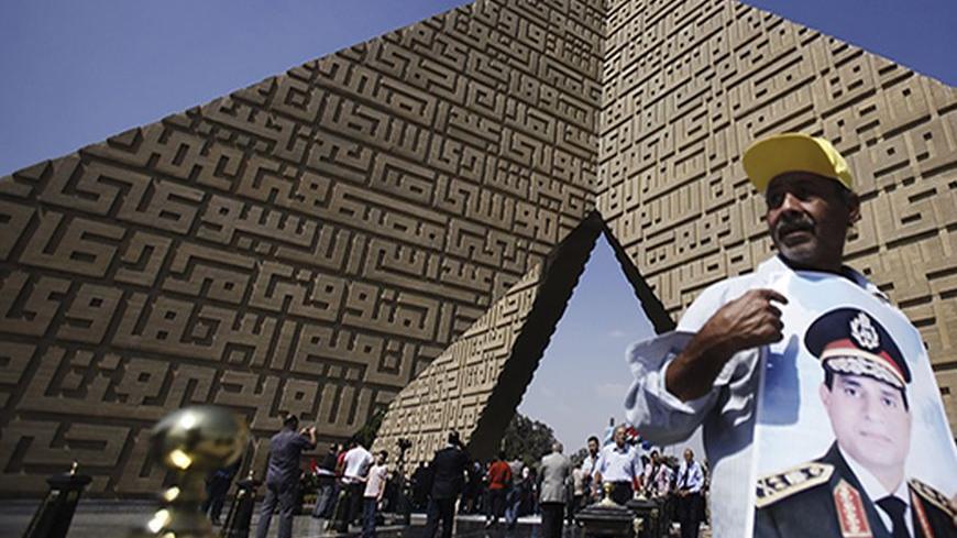 A man holds a poster Army Chief General Abdel Fattah al-Sisi at the tomb of late Egyptian President Anwar Sadat, during the 40th anniversary of Egypt's attack on Israeli forces during the 1973 war, at Cairo's Nasr City district, October 6, 2013. REUTERS/Amr Abdallah Dalsh  (EGYPT - Tags: POLITICS CIVIL UNREST MILITARY ANNIVERSARY) - RTR3FNLW