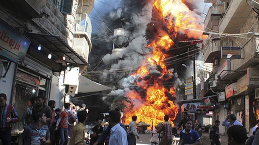 Residents run from a fire at a gasoline and oil shop in Aleppo's Bustan Al-Qasr neighbourhood October 20, 2013. Witnesses said the fire was caused by a bullet fired by a sniper loyal to Syrian President Bashar al-Assad at the Karaj al-Hajez crossing, a passageway separating Aleppo's Bustan al-Qasr, which is under the rebels' control and Al-Masharqa neighborhood, an area controlled by the regime. REUTERS/Haleem Al-Halabi (SYRIA - Tags: DISASTER TPX IMAGES OF THE DAY) - RTX14HWX