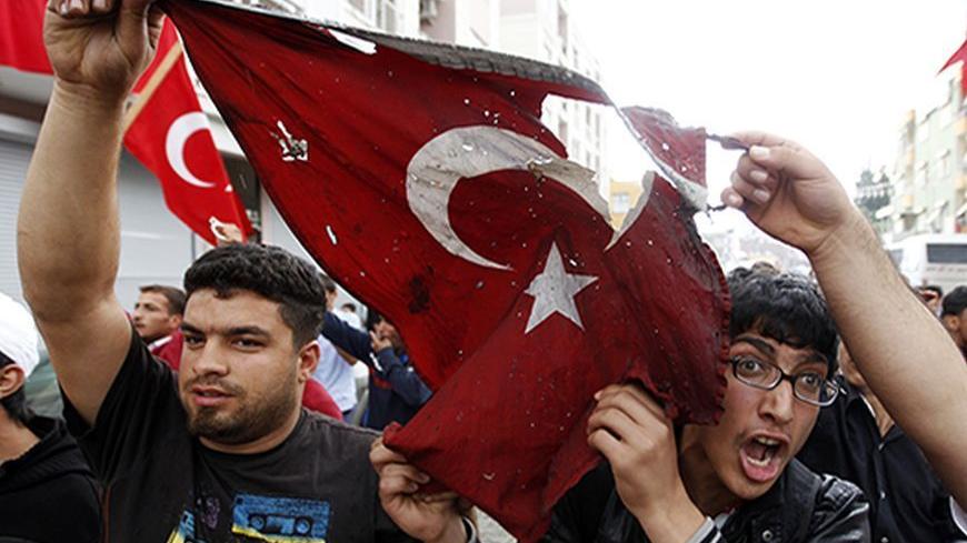 Turkish protesters march with a burnt national flag as they shout slogans against Prime Minister Tayyip Erdogan during a demonstration against the Turkish government's policy on Syria, in the town of Reyhanli in Hatay province, near the Turkish-Syrian border, May 13, 2013. Syria's information minister has blamed Turkey's government for deadly car bombings near the Syrian border and branded Prime Minister Tayyip Erdogan a "murderer", state-run Russian TV company RT reported on Monday. It said he repeated a d