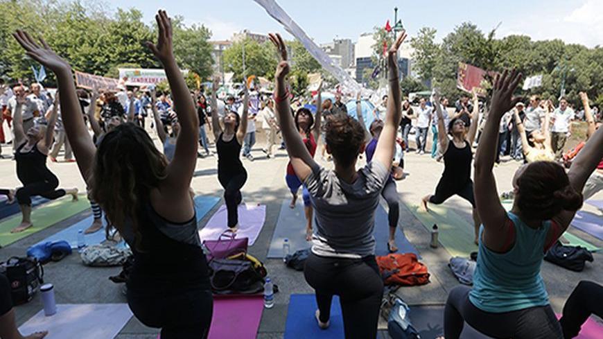 People practice yoga in Gezi Park at Taksim Square in Istanbul June 7, 2013. Istanbul's Gezi Park, yoga practitioners stretch and students read in a makeshift library - a statement of their intent to stay on after a week of protests. At night demonstrators taunt riot police from beyond barricades on the streets around Taksim Square. Those in its Gezi Park hold sit-down protests and discuss Turkey's future.   REUTERS/Osman Orsal (TURKEY - Tags: CIVIL UNREST POLITICS SOCIETY) - RTX10FAH
