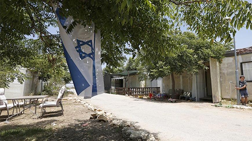 A boy stands near an Israeli flag in the West Bank Jewish settlement of Ofra, north of Ramallah July 18, 2013. Negotiations between Israel and the Palestinians, which have ebbed and flowed for two decades, last broke down in late 2010, after a partial settlement halt meant to foster talks ended and Israeli Prime Minister Benjamin Netanyahu refused to extend it. Palestinians familiar with Palestinian President Mahmoud Abbas' thinking speculated he might now forgo the demand for a settlement moratorium given 