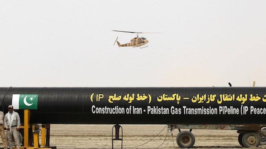 Irani workers stand near as a security helicopter lands near the pipeline during a groundbreaking ceremony to mark the inauguration of the Iran-Pakistan gas pipeline, in the city of Chahbahar in southeastern Iran March 11, 2013. Ahmadinejad and Zardari marked the start of Pakistani construction on the much-delayed gas pipeline on Monday, Iranian media reported, despite U.S. pressure on Islamabad to back out of the project. REUTERS/Mian Khursheed (IRAN - Tags: POLITICS ENERGY) - RTR3EUW9