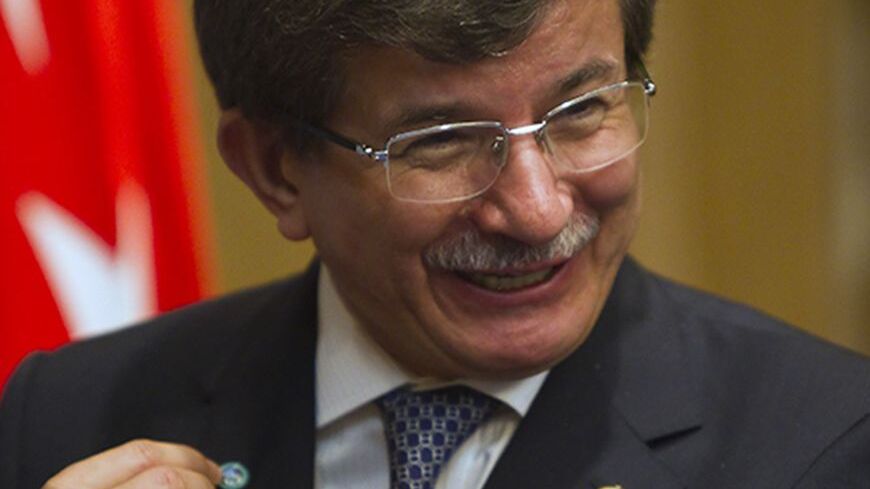 Turkey's Foreign Minister Ahmet Davutoglu shows a Shanghai Cooperation Organisation (SCO) pin after a signing ceremony granting Turkey a partner status in SCO, in Almaty April 26, 2013.  REUTERS/Shamil Zhumatov  (KAZAKHSTAN - Tags: POLITICS BUSINESS) - RTXZ0SB