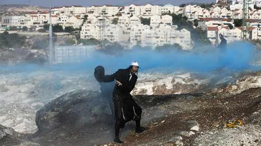 An Ultra-Orthodox protester protects himself as Israeli police (not pictured) fire a water cannon to disperse protesters during clashes in the town of Beit Shemesh, near Jerusalem August 14, 2013. Ultra-Orthodox protesters clashed on Wednesday with police and other security forces in the town of Beit Shemesh after a group of them broke into a construction site to prevent work from taking place at the site they believe contains ancient graves. REUTERS/ Baz Ratner (ISRAEL - Tags: RELIGION CIVIL UNREST POLITIC