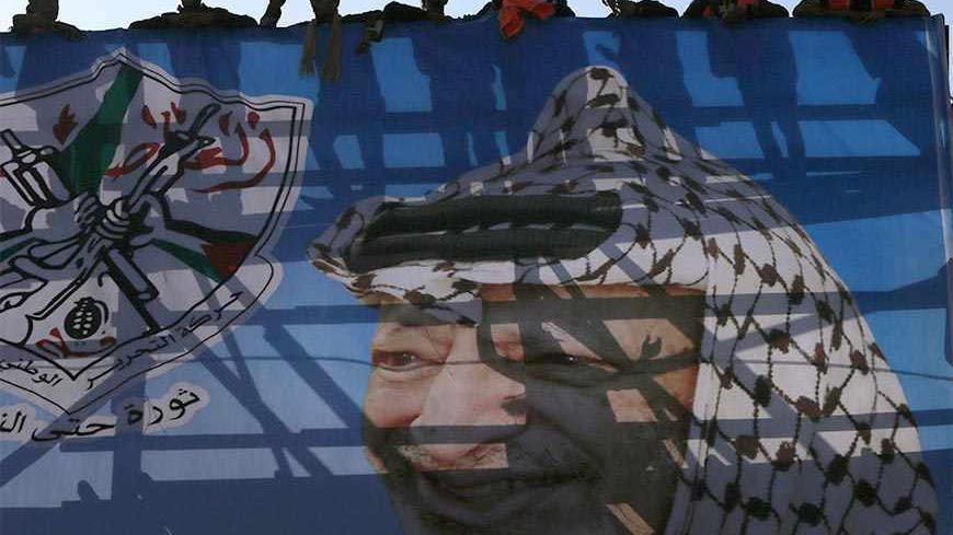 Palestinians stand on a stage with a poster depicting late Palestinian leader Yasser Arafat during a rally marking the 48th anniversary of the founding of the Fatah movement, in Gaza City January 4, 2013. Hundreds of thousands of Palestinians joined a rare rally staged by President Mahmoud Abbas's Fatah group in Gaza on Friday, as tensions ease with rival Hamas Islamists ruling the enclave since 2007. REUTERS/Suhaib Salem (GAZA - Tags: POLITICS ANNIVERSARY) - RTR3C3I8